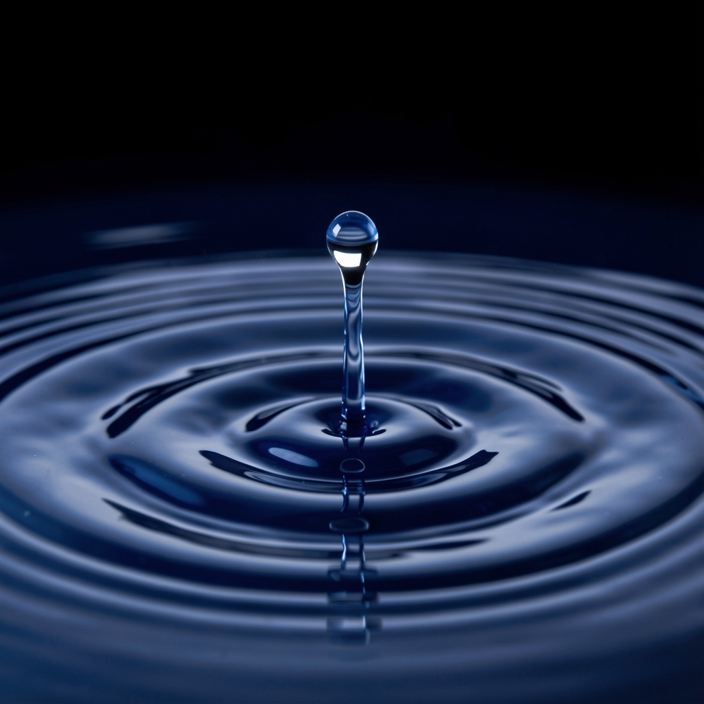 Gota de agua cristalina cayendo sobre superficie líquida azul oscuro creando ondas concéntricas perfectas con fondo oscuro, fotografía macro de alta precisión